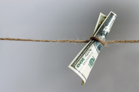 A hundred dollar bill hanging from a rope.