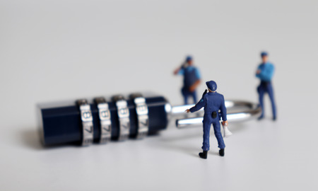 A combination lock and miniature people.の写真素材