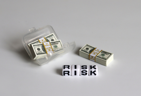 A white cube with 'RISK' text and a hundred-dollar bills.の写真素材