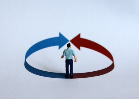 A miniature man standing in front of a circle with an arrow.の写真素材