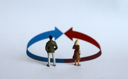 A miniature man and a miniature woman standing in front of a circle with an arrow.