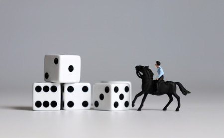 Miniature man riding a horse and white dice. Concepts about the probability of winning a race.の写真素材