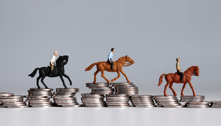 Miniature horse rider on pile of coins. A sports gambling concept.の写真素材
