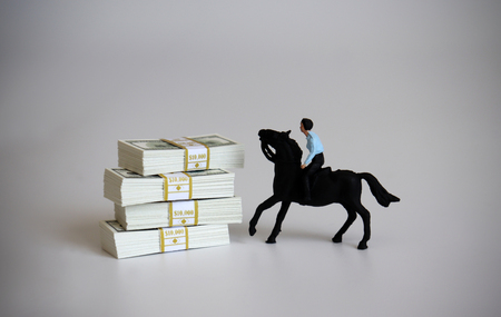 A miniature rider riding and wad of $ 100 bills.の写真素材