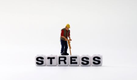 The word STRESS on white cubes with miniature people.の写真素材