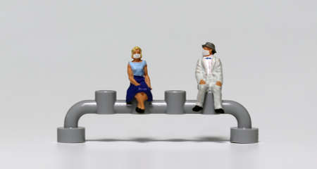 Miniature people sitting wearing masks. Concepts about the importance of wearing a mask and sitting apart.の写真素材