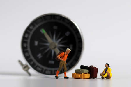 A miniature man standing in front of the compass and a miniature woman sitting with luggage. Compass...