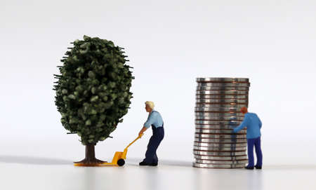 Piles of coins and miniature tree and miniature people.の写真素材