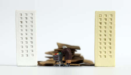 A miniature old woman pulling a cart between buildings. The concept of the extreme gap between the...