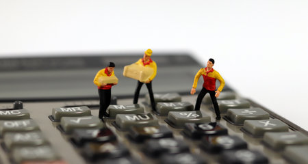 Three miniature couriers standing on a calculator.の写真素材