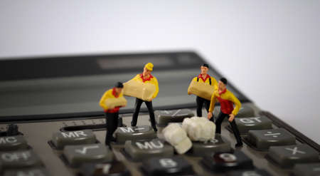 Four miniature couriers standing on a calculator.の写真素材