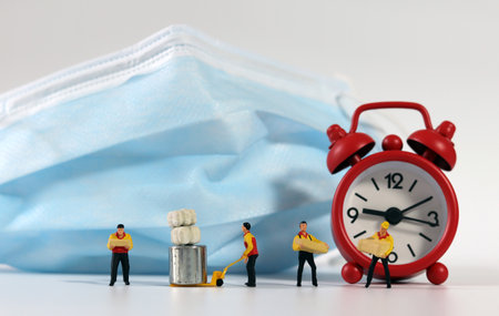 Miniature deliverymen holding parcels, red alarm clock.の写真素材