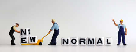 The concept of preparing a New Normal. Two miniature men carrying NEW on a cart.の写真素材