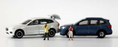 Two miniature cars collided and two miniature people calling. Concepts about car accidents and miniature people.の写真素材