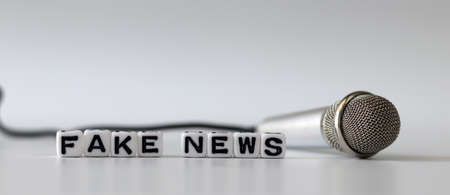 White dice and'FAKE NEWS' with News, solution and business concepts on white background. White cube and miniature microphones.の写真素材
