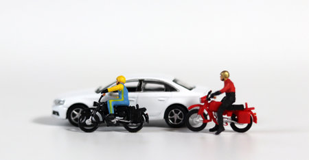 Miniature people and miniature car. White cars and fallen motorcycle drivers. Concept about the...