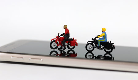 Two miniature motorcycle riders on the smartphone. Concept about useful online delivery.の写真素材