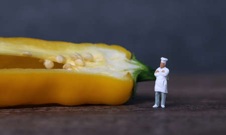A miniature chef standing and yellow paprika. The concept of miniature people and fresh ingredients.の写真素材