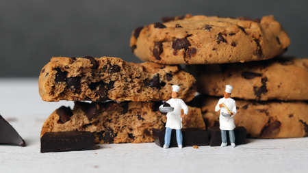 Fresh chocolate cookies baked in the oven and two miniature chefs. Miniature people and chocolate cookies with business concept.の写真素材