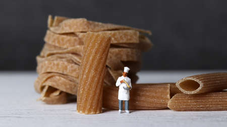 Close-up images of whole wheat pasta and miniature people. The miniature people and pasta noodles with Business concept.の写真素材