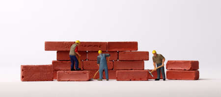 Miniature workers building bricks. Business concept with bricks and miniature people.の写真素材
