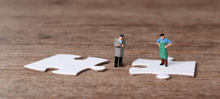 White puzzle pieces and miniature people with business concept. Miniature man standing on a puzzle.