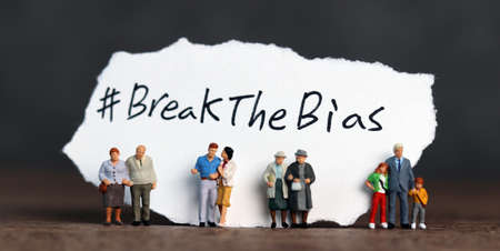 Torn paper with the word '#BreakTheBias' written on it. Break the bias campaign with miniature several people.の写真素材