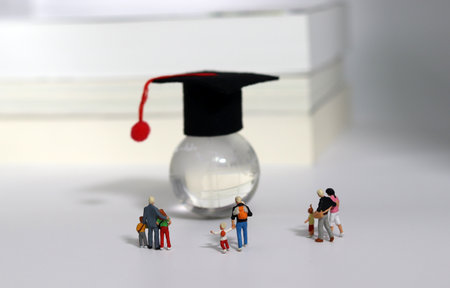 The concept of interest in global early education. Miniature people looking at a globe with graduation caps on it.の写真素材