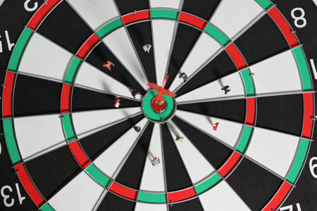 Business goals and concepts for achievement and victory. Miniature entrepreneurs meeting on dart boards where red dart arrows hit the center.の写真素材