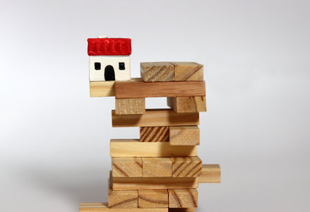 A house is placed on a wooden block. Instability in the real estate market. The concept of real...
