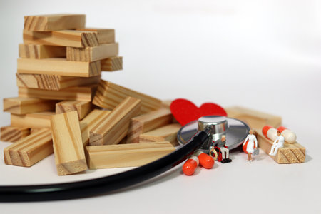 Miniature patients and medics, stethoscopes and hearts between collapsed blocks. The concept of...