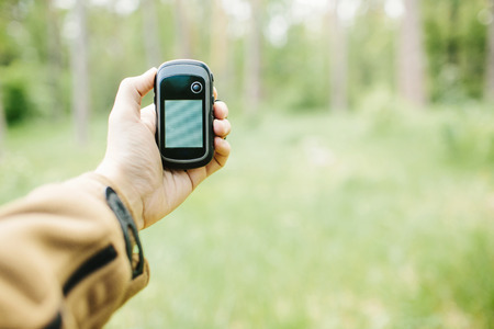 Man holding a GPS receiver and plan in his hand. Handheld GPS devices are used predominantly in the outdoor leisure industry for walking and hiking.の写真素材