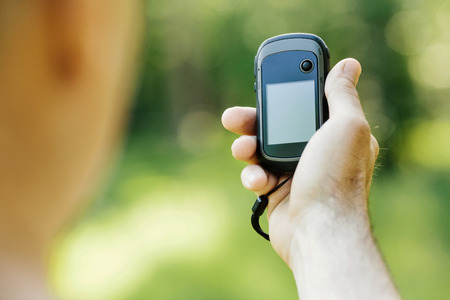 Man holding a GPS receiver and plan in his hand. Handheld GPS devices are used predominantly in the outdoor leisure industry for walking and hiking.の写真素材