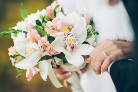 A close up of a bride and groom holding a bouquet of white and pink flowersの写真素材