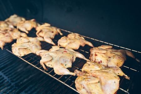 Seasoned chickens roasting on a charcoal grillの写真素材