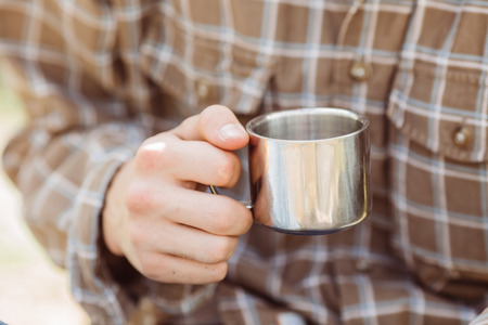 A person holding a titanium cup of tea while campingの写真素材