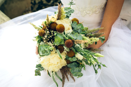 A close up of a bride holding a beautiful bouquet of white field flowersの写真素材