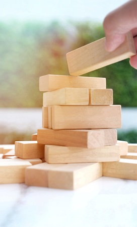 Selective focus at the hand try to building wooden block puzzle on the table / Closeup of blocks...
