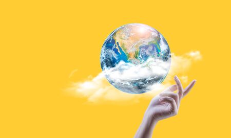 Hand holding earth on yellowの写真素材