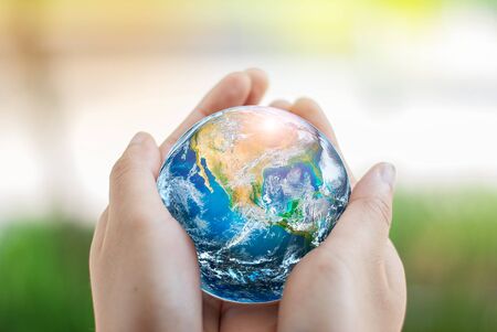 Hand holding earth globe on green