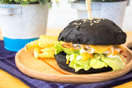 Black Burger with fries and sauce on wooden deskの写真素材