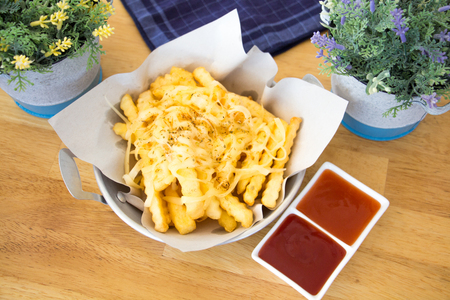 pan with tasty cheese fries on wooden background