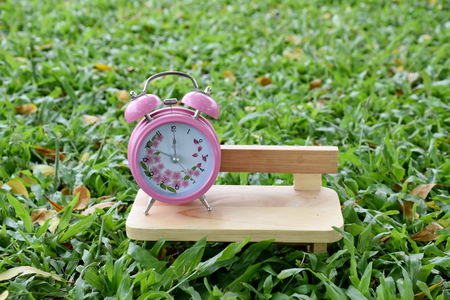 Pink alarm clock outdoors sitting in chair on the lunch of a bright sunny day.の写真素材