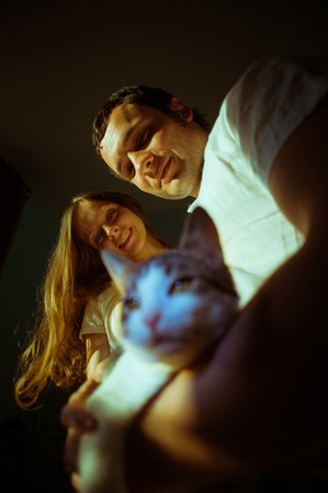 Couple expecting baby. Happy future dad and his cheerful caucasian pregnant wife stand opposite to a window at home and dream of the future.の写真素材