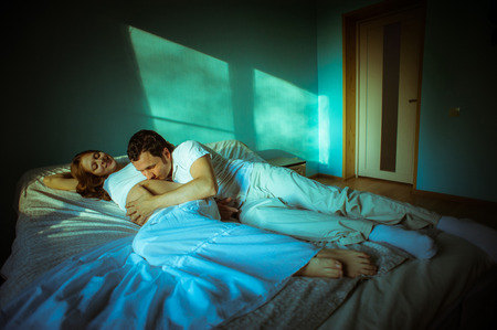 Image of happy future dad kiss the belly of his cheerful caucasian pregnant wife lying on bed at home.の写真素材