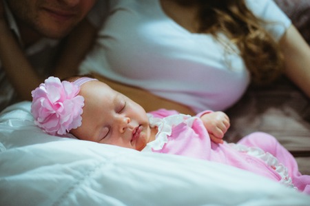 Image of cute little girl on lap of young mother. Mum and baby. Infant child in pink suit.の写真素材