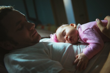 Image of young dad with cute little daughter in his arms. Father and newborn baby child indoor.の写真素材