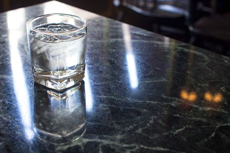 Water glass with some ice on the tableの写真素材