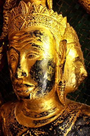 High contrast image of golden face buddha sculptures on the temple entrance gate, Phra Mahathat Temple, Nakonsrithamarat, Thailandの写真素材