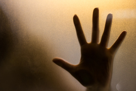 Shadow of hand behind wet glass, close-upの写真素材